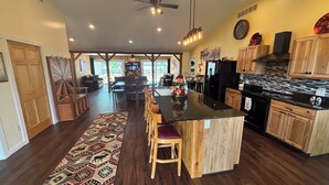 A spacious kitchen with wooden cabinets, a central island with stools, and a dining area with a patterned rug. - Rusty’s Getaway is a rustic/modern handicap accessible, family friendly space.  (Findlay)