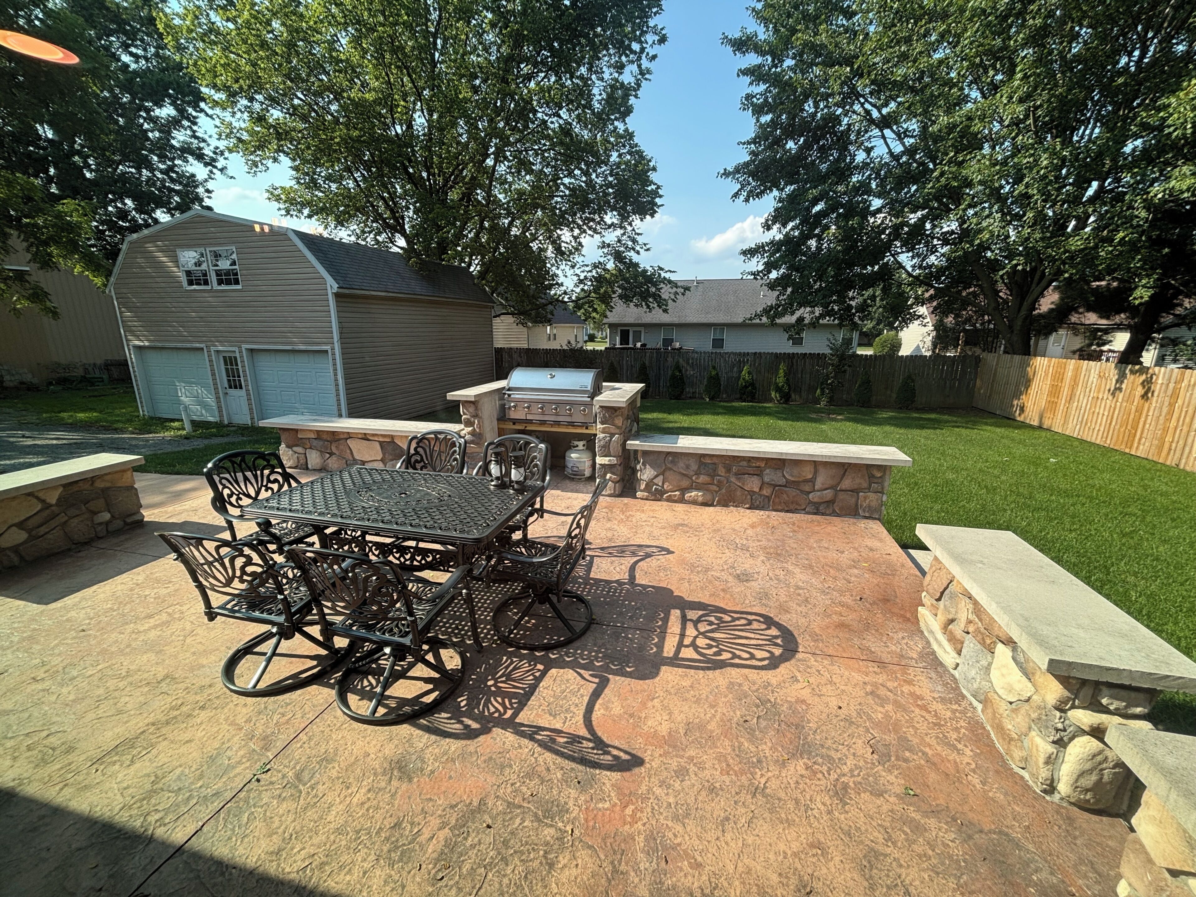 Une terrasse extérieure avec une table et des chaises, un barbecue et un mur en pierre.