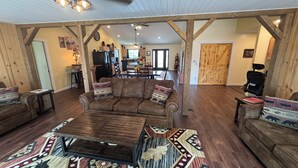 A spacious living area with a large brown sofa, a coffee table, and a patterned rug. There is a wooden dining table and chairs in the background. - Rusty’s Getaway is a rustic/modern handicap accessible, family friendly space.  (Findlay)