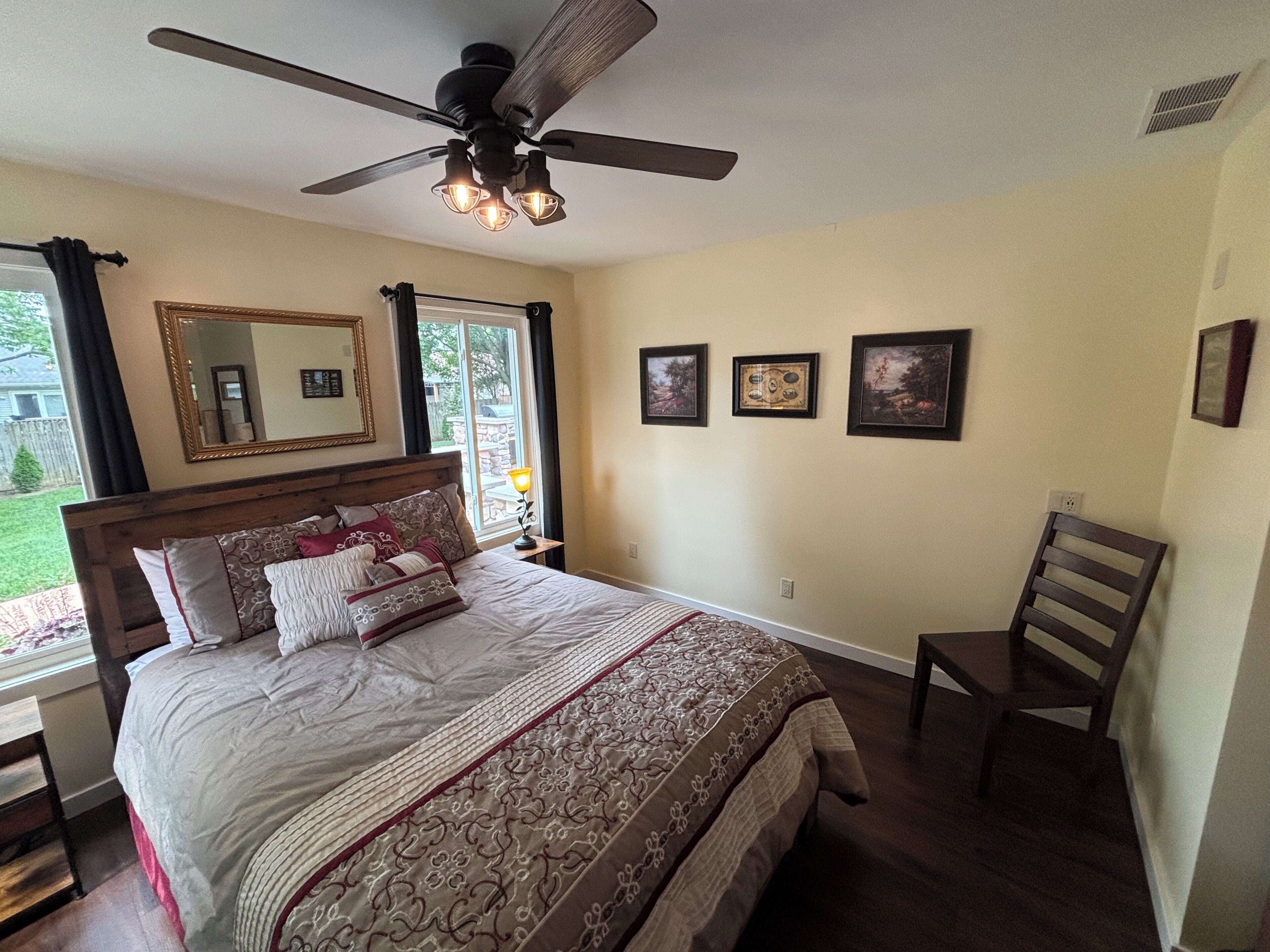 Une chambre à coucher avec un lit, une chaise, un ventilateur de plafond et une fenêtre.