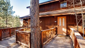 A wooden cabin with a wooden deck and a large tree in front. - Condo within walking distance of the Chile Express (Angel Fire)