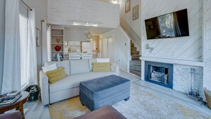 A spacious living area with a sofa, ottoman, and a fireplace. - Condo within walking distance of the Chile Express (Angel Fire)