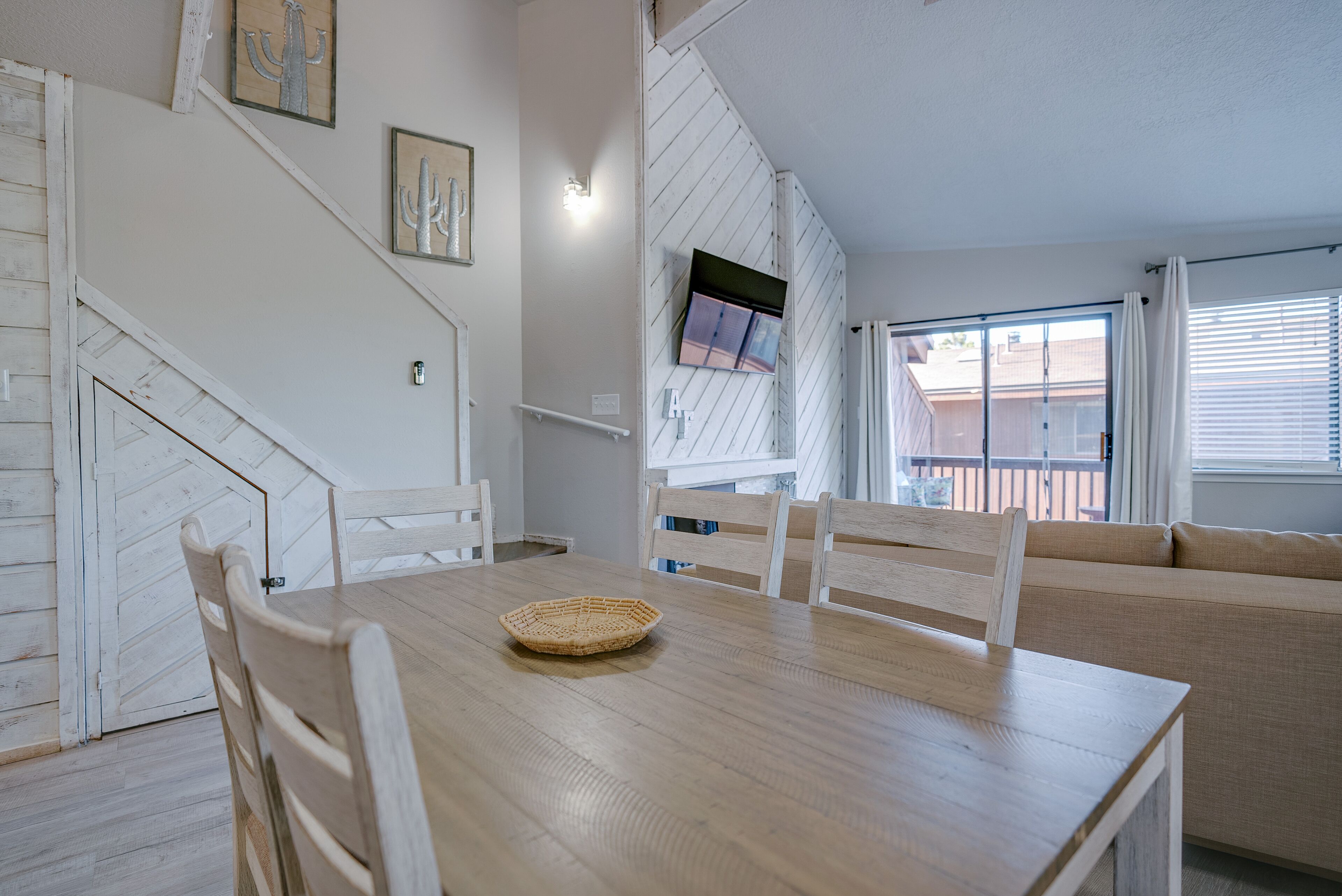 A dining area with a wooden table, white chairs, and a woven placemat.
