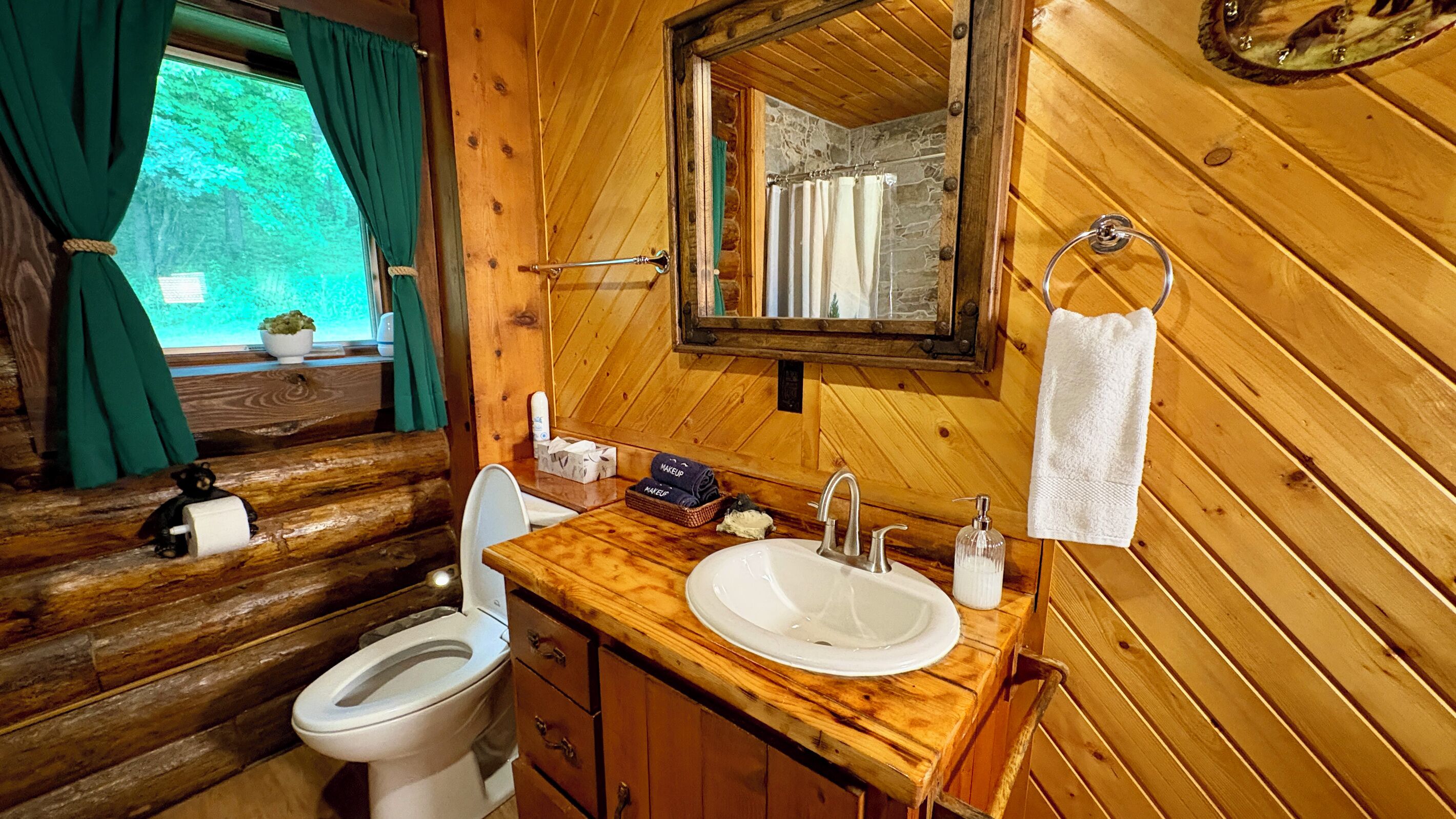 Un baño de cabaña de madera con inodoro, lavabo y espejo.