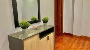 Ein modernes Badezimmer mit einem Holzwaschtisch, einem großen Spiegel und zwei Zimmerpflanzen.