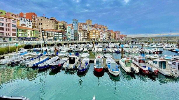 A marina with numerous boats docked, surrounded by colorful buildings.