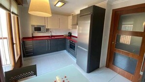 A compact kitchen with a refrigerator, microwave, and a sink.