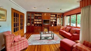 A living room with wooden furniture, a glass coffee table, and a bookshelf. - Amatxo Maitia - Large movie apartment. (Bilbao)
