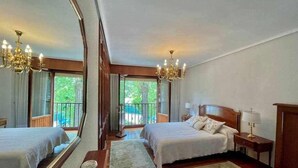 A hotel room with two beds, a large mirror, a chandelier, a nightstand, and a view of the outdoors. - Amatxo Maitia - Large movie apartment. (Bilbao)