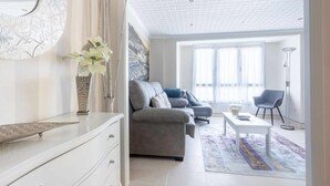 A modern living room with a grey sofa, a white coffee table, and a patterned rug. - Old Port, Apartamento con Vistas al Puerto (Bermeo)