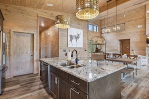 A spacious kitchen with a large island, wooden walls, and modern lighting fixtures. - Rainbow Ridge: A Modern Luxurious 4-Bed Cabin: Private Heated Pool, Hot Tub, Game Room, Theater. (Sevierville)