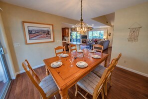 Uma sala de jantar com mesa de madeira posta para seis pessoas, rodeada por cadeiras de madeira com assentos acolchoados.