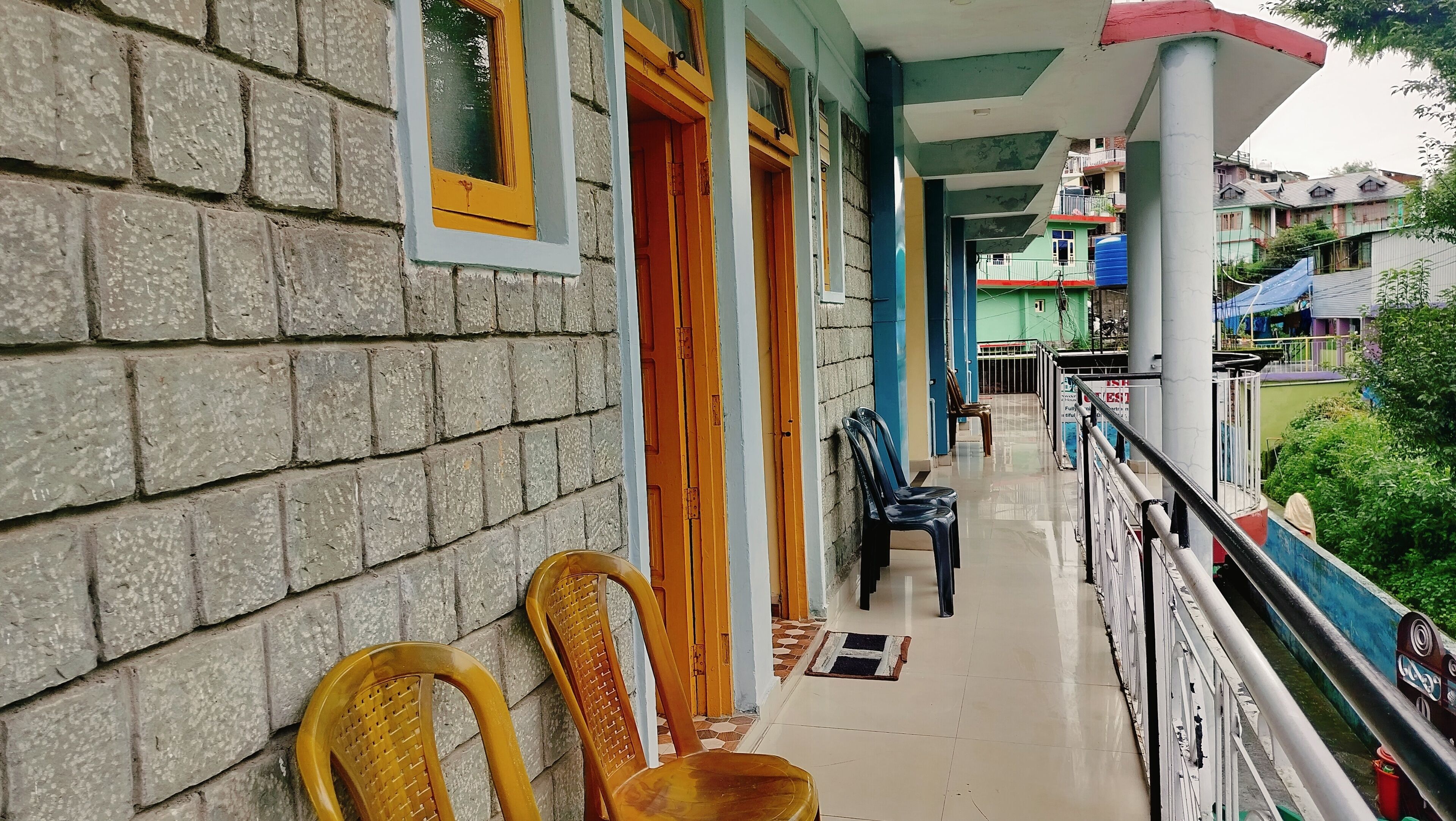Uma varanda com piso de azulejos, duas cadeiras de vime e um corrimão.