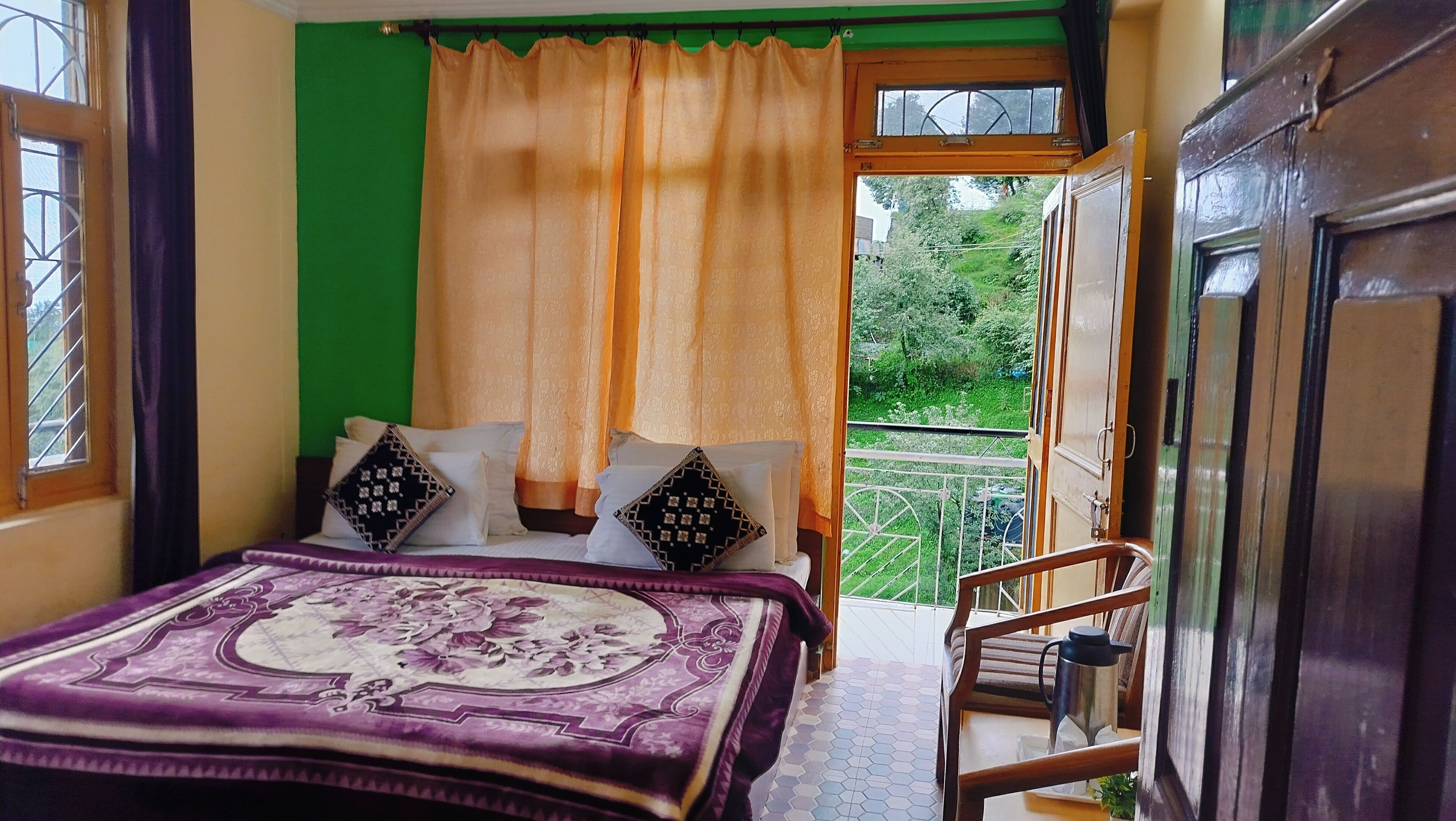 A bedroom with a bed, pillows, a window, and a view of greenery outside.