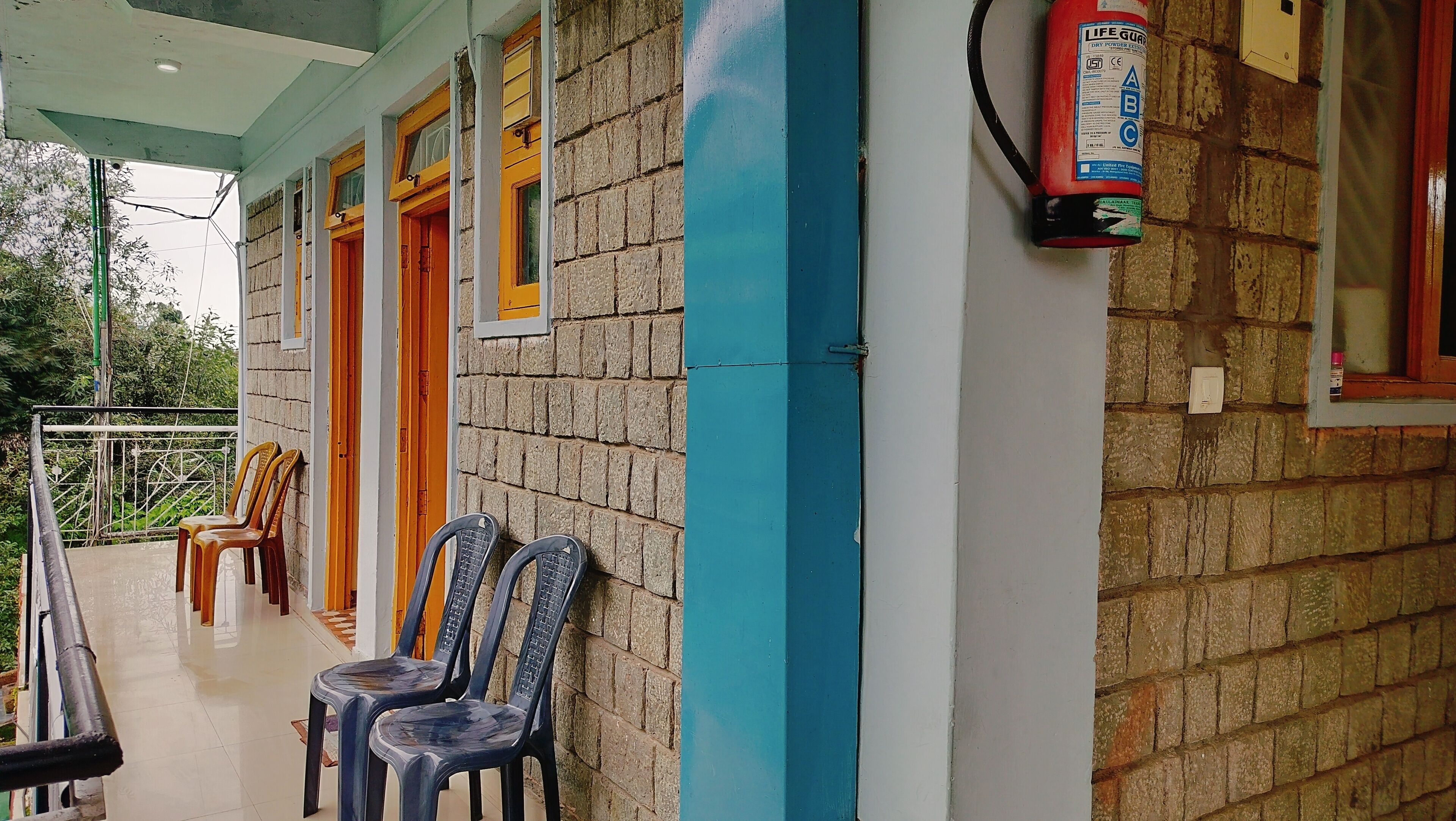 A building with a brick exterior, a blue vertical stripe, and a fire extinguisher mounted on the wall.