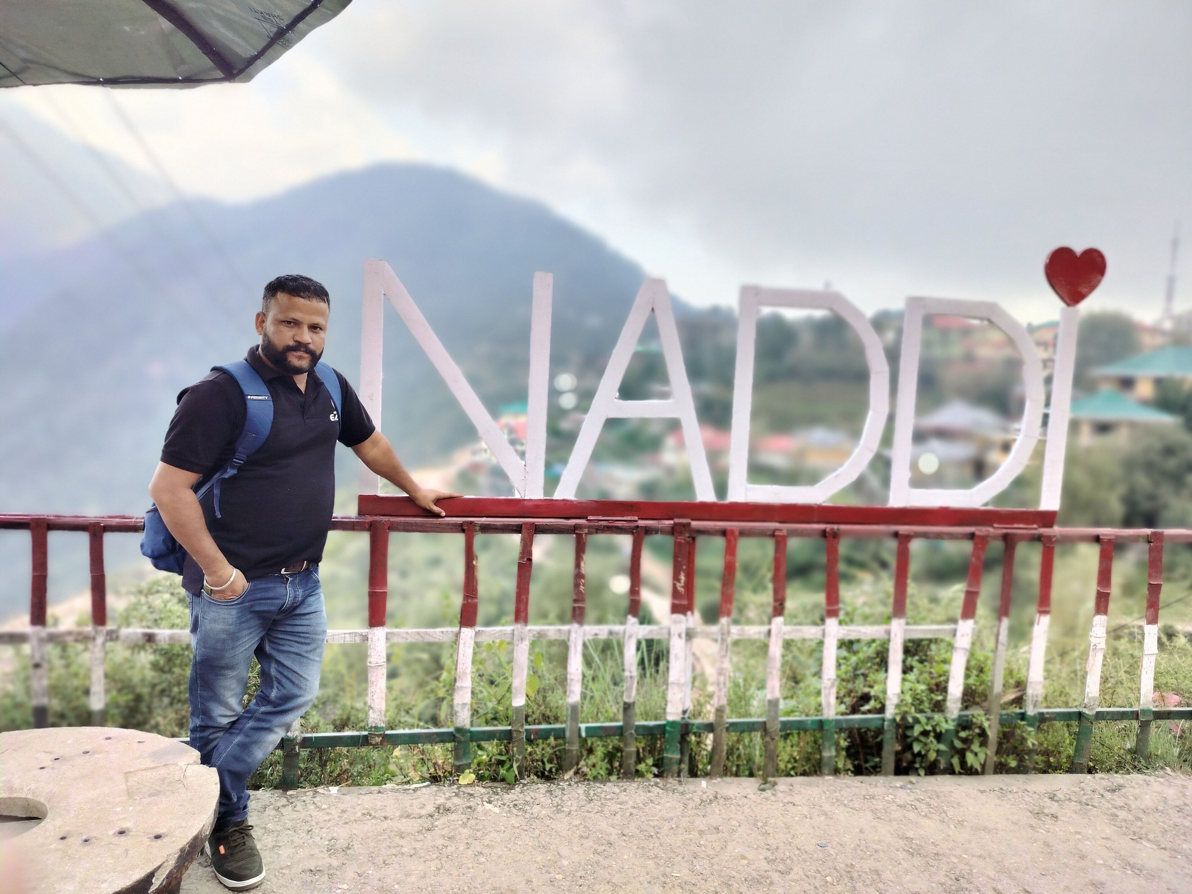 A man standing by a sign with the name "NADDI" and a heart symbol.