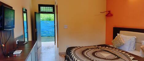 A hotel room with a bed, a TV, a desk, and a view of the outside.