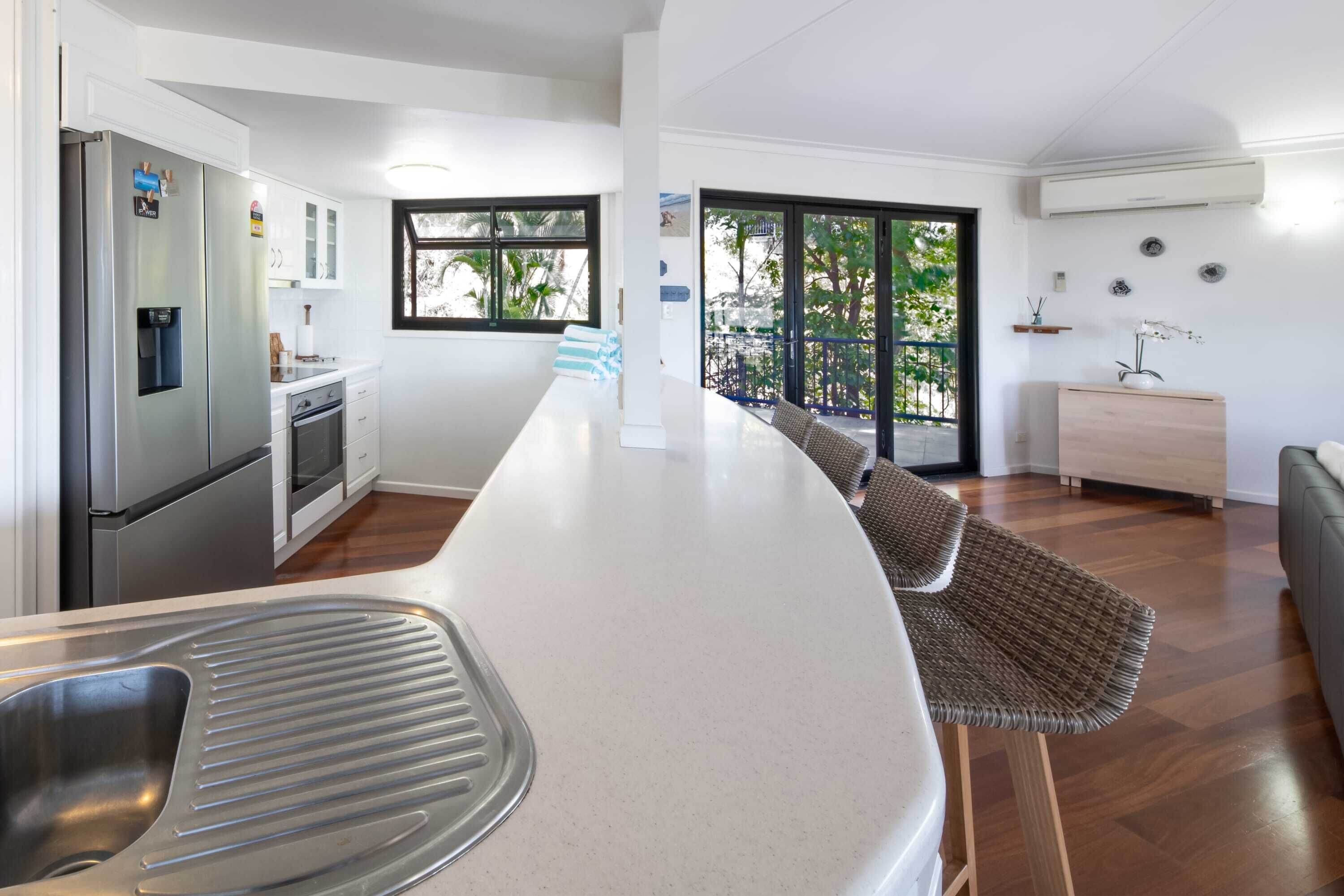 A modern kitchen with a central island, stainless steel appliances, and a view to the outside.