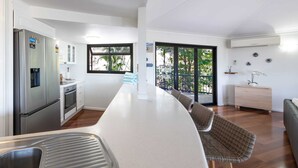 A modern kitchen with a central island, stainless steel appliances, and a view to the outside.