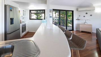 A modern kitchen with a central island, stainless steel appliances, and a view to the outside.