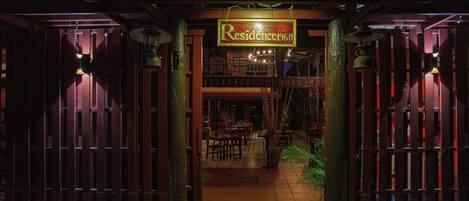 Una verja de madera con un letrero que dice "Residence1960" que da acceso a un comedor con mesas y sillas.