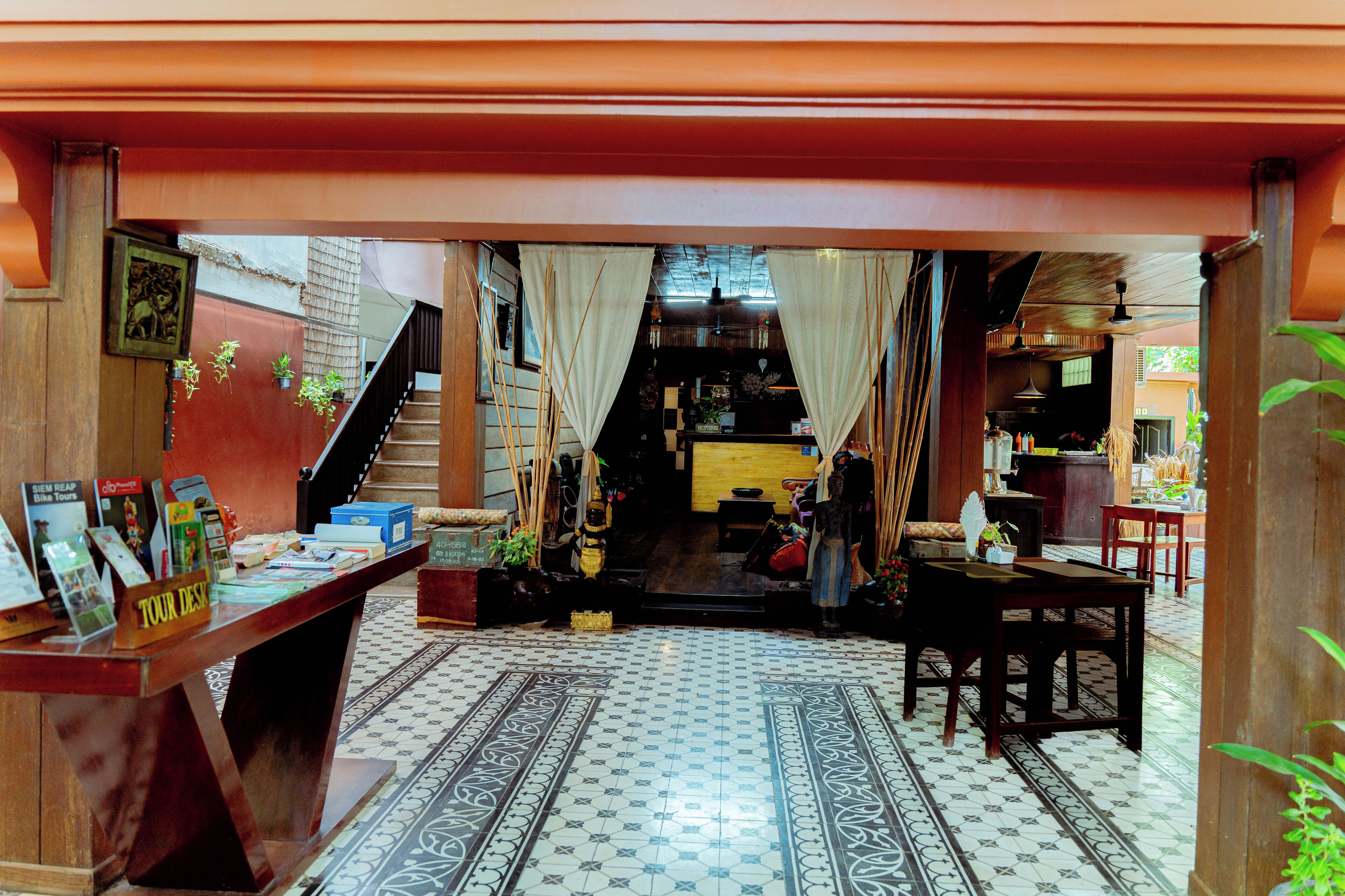 A traditional interior with a tiled floor, a wooden desk with brochures, and a staircase leading to an upper level.
