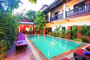 Una piscina al aire libre, sombrillas, sillones reclinables de piscina