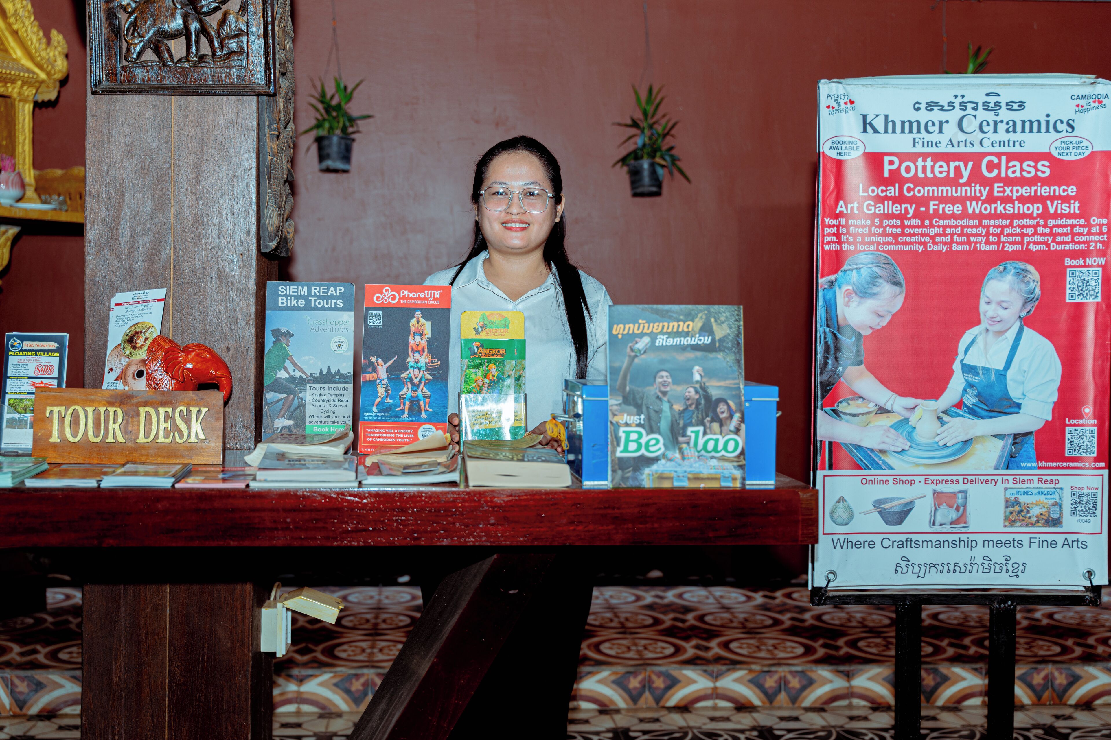 A display table with various travel brochures and a sign for a pottery class.