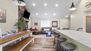 A spacious living area with a wooden bench, a stone fireplace, and a large window. - Lakefront Luxury! Direct Water Access, Spa, Fire Pit & Boat Launch-Sleeps 17 (Rogers)