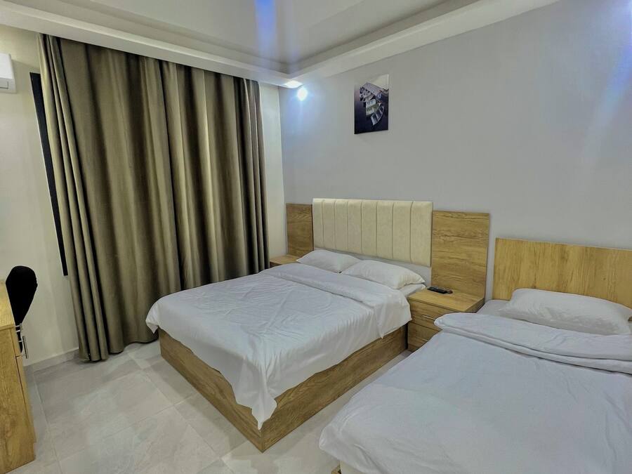 A hotel room with two beds, a wooden headboard, a white ceiling, and a small picture on the wall.