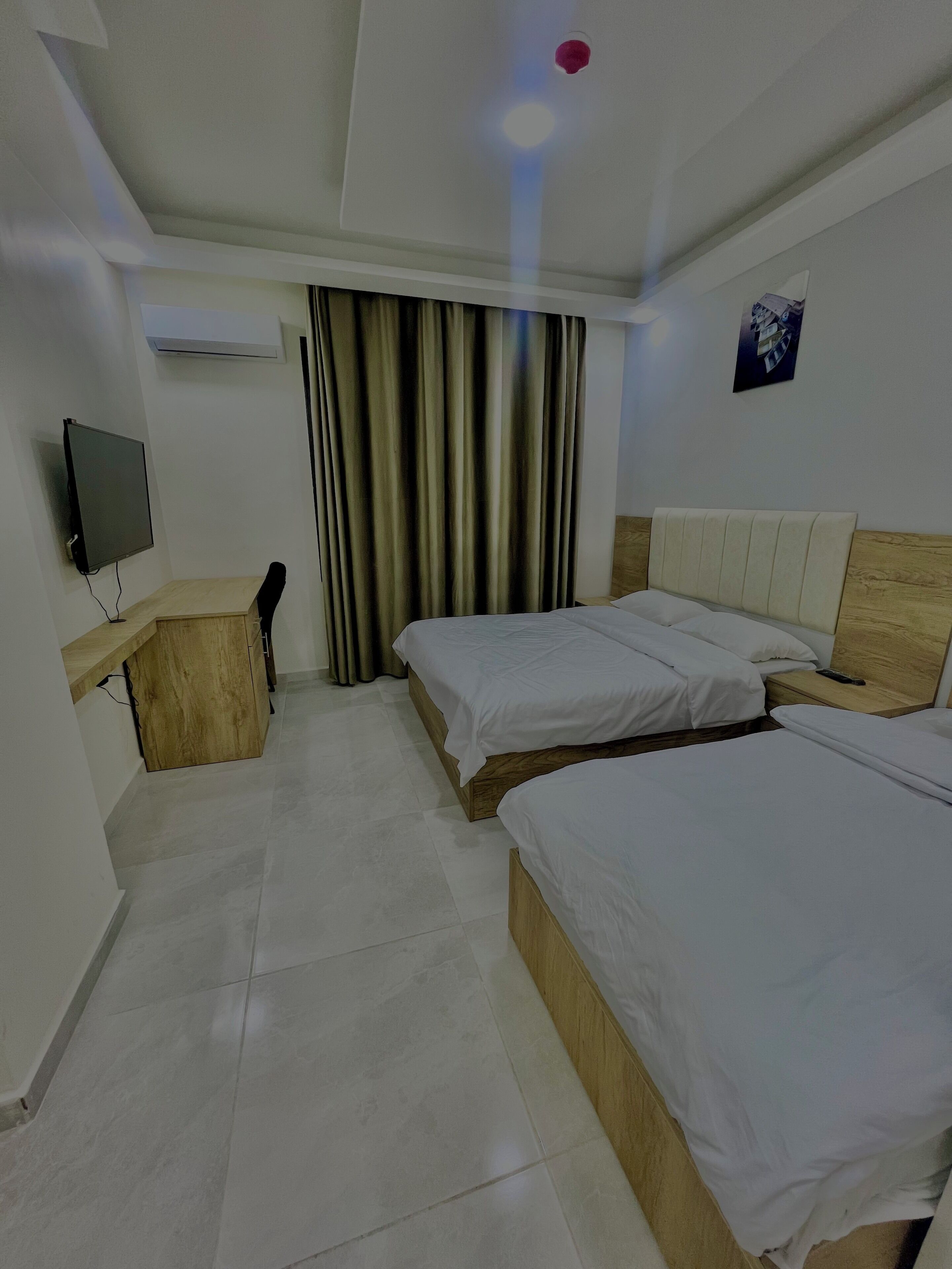 Una camera d'albergo con due letti, una scrivania con un computer e una televisione.