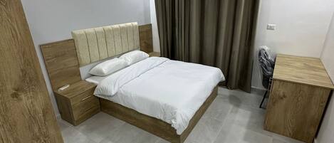 Un dormitorio moderno con cabecera de cama de madera, una mesita de noche, un armario de madera y una lámpara de techo.