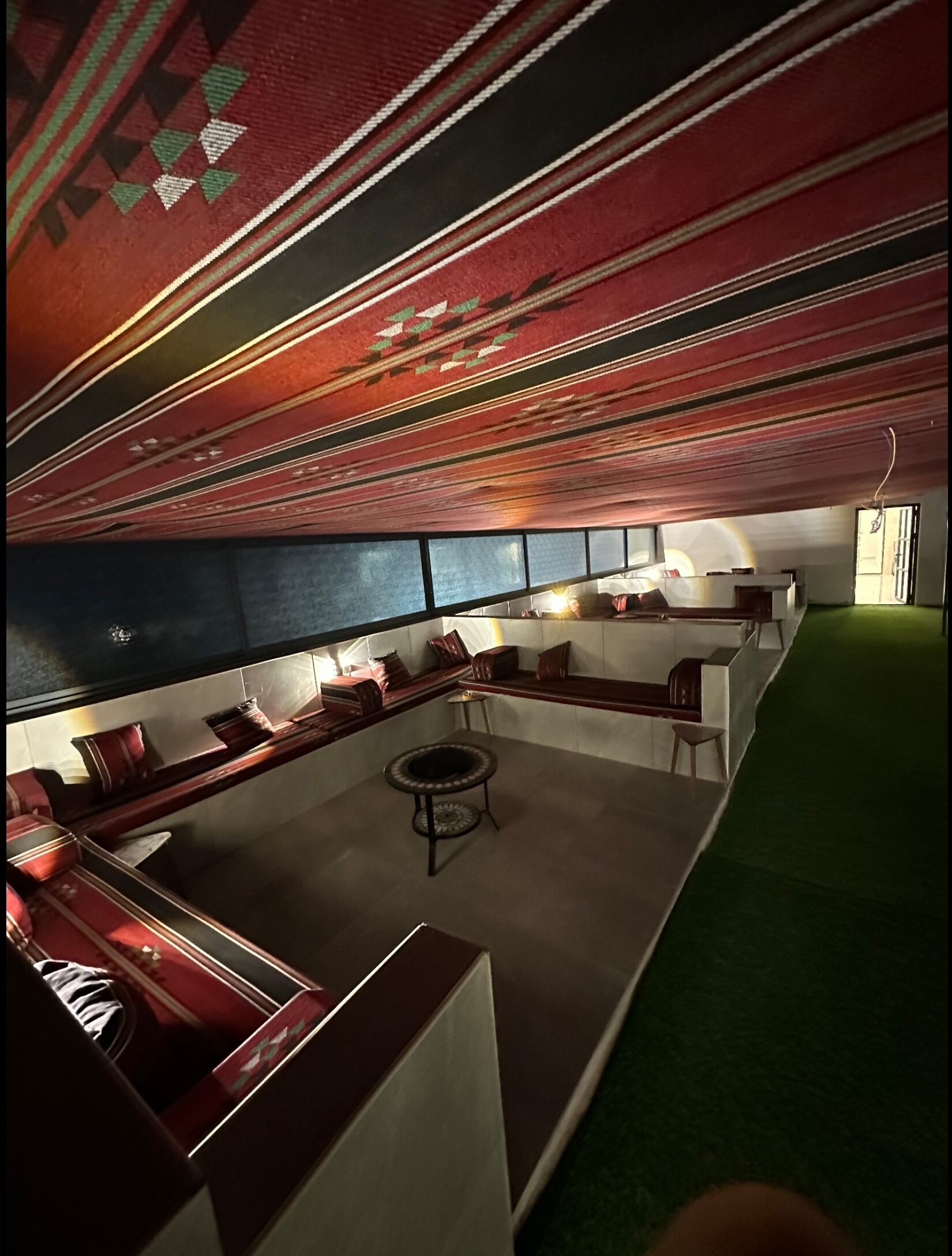 Una zona d'estar moderna amb un sostre amb dibuixos, una taula de cafè rodona i un sofà.