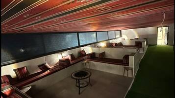 Una zona d'estar moderna amb un sostre amb dibuixos, una taula de cafè rodona i un sofà.