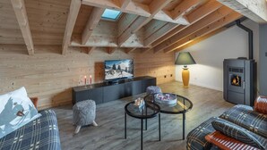 Um quarto acolhedor no estilo loft, com vigas de madeira aparentes, televisão, lareira e um espaço de estar confortável.