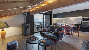 Uma sala de estar aconchegante com lareira, um espaço para refeições e uma cozinha com vista para as montanhas.