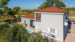 Un bâtiment à deux étages, doté d’un toit recouvert de tuiles rouges, d’une piscine et d’une antenne parabolique.
