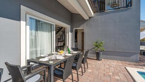 Une terrasse extérieure avec une table à manger pour quatre personnes, entourée de chaises en osier.