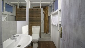 Une petite salle de bain avec un lavabo, des toilettes et une douche, le tout de couleur blanche.