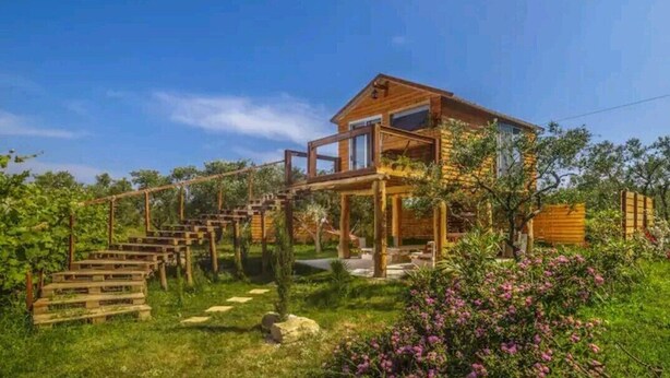 Une maison en bois dotée d’un balcon et d’un escalier en bois menant à l’entrée.