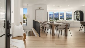 A modern interior with a dining area, a sofa set, and large windows offering a mountain view.