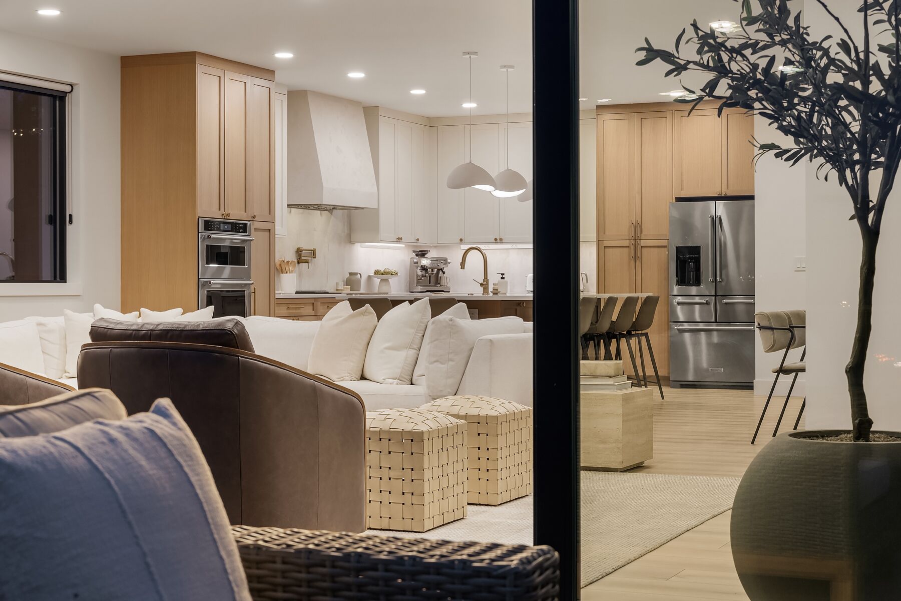 Uma sala de estar moderna com sofá, pufes e um espaço de jantar com cadeiras e mesa.