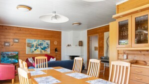 A cozy dining area with a wooden table and chairs, a blue sofa, and a painting on the wall. - Urupää b 6 by Interhome (Inari)