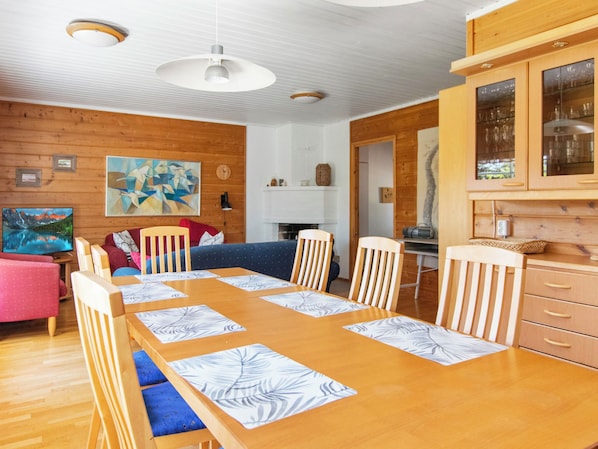 Un comedor acogedor con una mesa y sillas de madera, un sofá azul y una zona de cocina con armarios y una estufa.