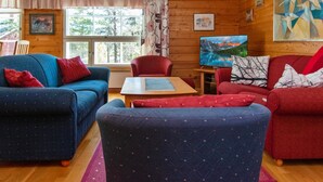 A cozy cabin interior with wooden walls, a large window, a TV, and a painting. - Urupää b 6 by Interhome (Inari)
