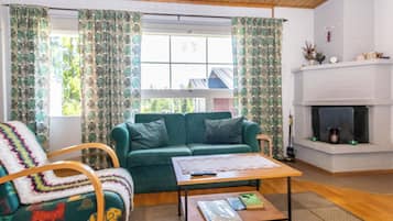 A cozy living room with a green sofa, a wooden coffee table, and a fireplace.