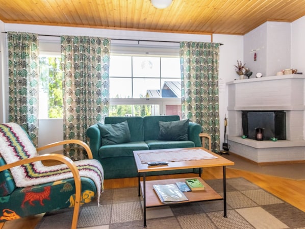 A cozy living room with a green sofa, a wooden coffee table, and a fireplace.