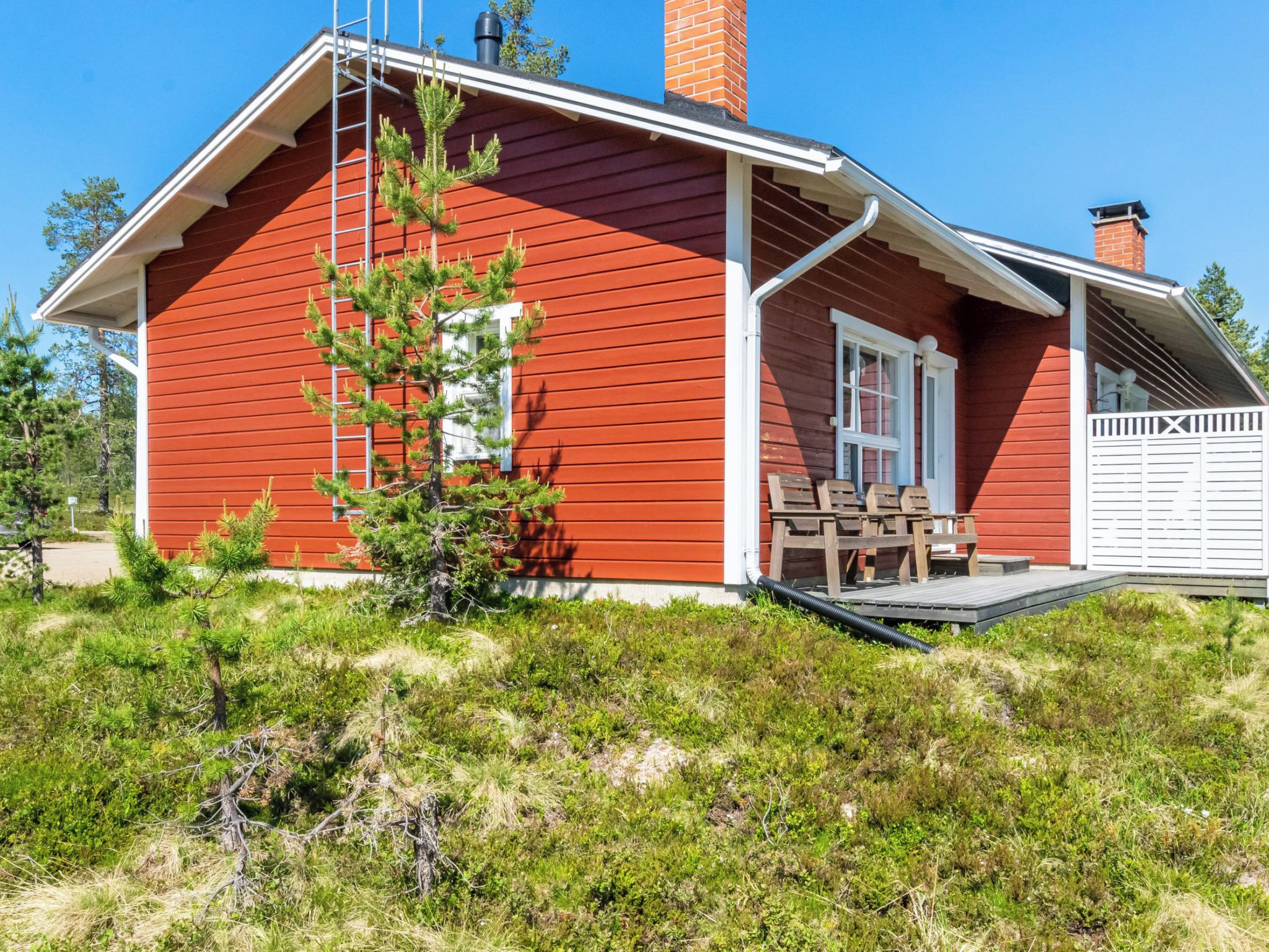 A red wooden house with a porch, a chimney, and a garage.
