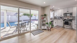 A modern kitchen with white cabinets, stainless steel appliances, and a tiled backsplash.