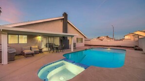 A swimming pool with a hot tub, outdoor seating, and a covered patio area.